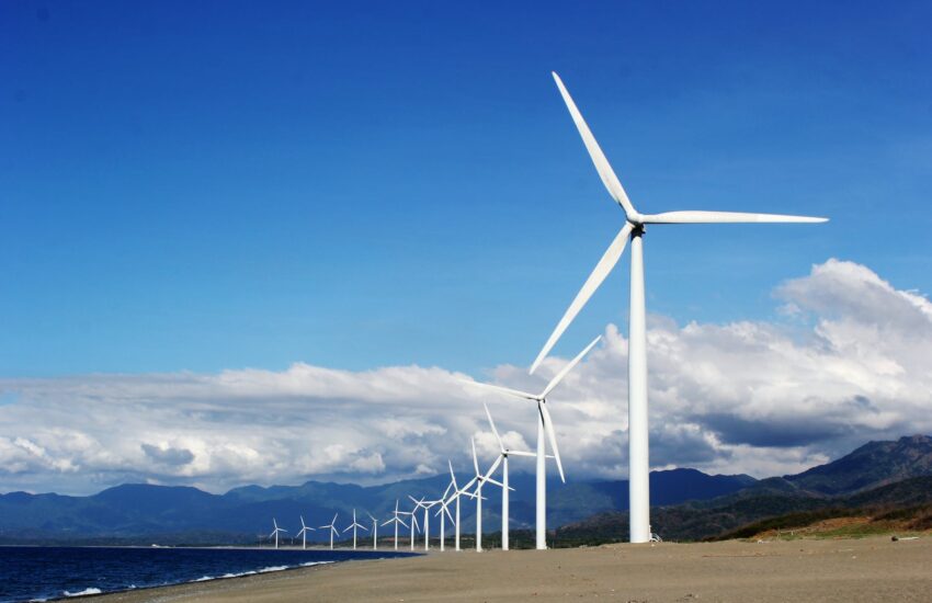 white wind turbines on gray sand near body of water